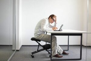 Jeune homme penché en avant sur son ordinateur, au travail